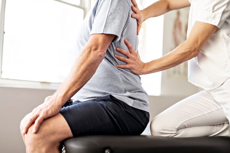 physiotherapist doing massage on the back of a senior patient