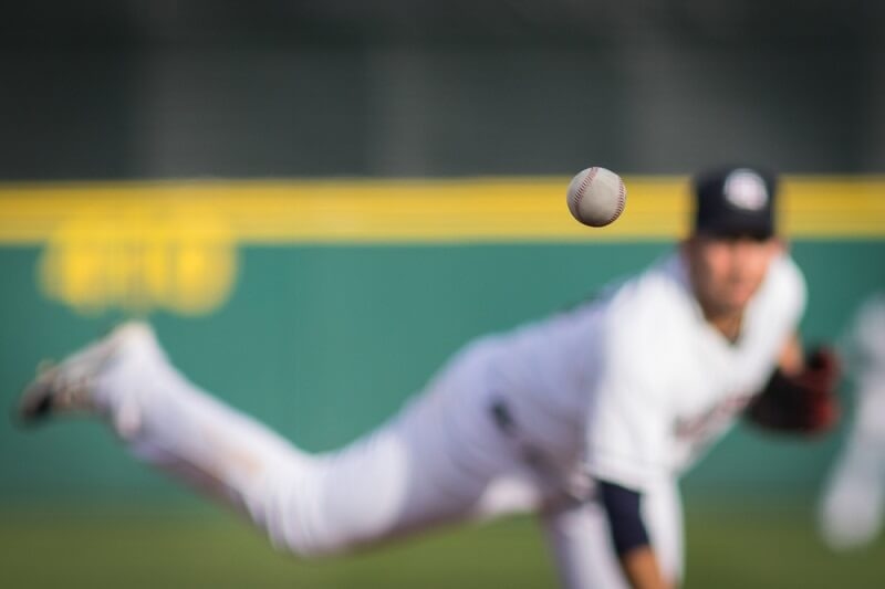 A baseball in motion with pitcher in background