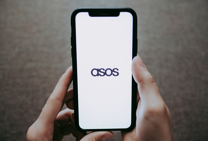 ASOS online clothing store, hands holding iPhone with screen asos app