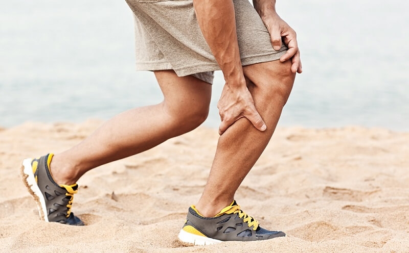 Athlete in sports shorts clutching his thigh muscles after pulling or straining them