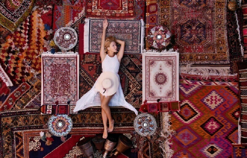 Beautiful girl in a long white dress laying on the carpet and rugs