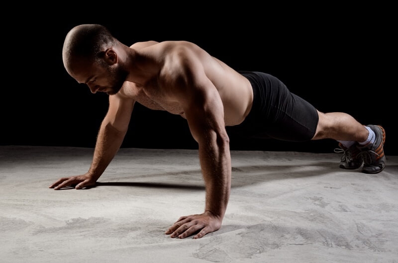 Boxer training push ups on a dark background