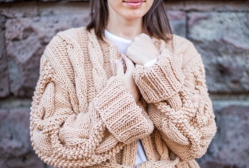 Closeup of woman wearing a beige soft oversized knitted sweater