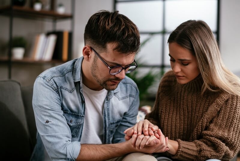 Couple hoding hands, Girl comforting her sad boyfriend.