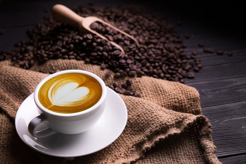 Cup of coffee with heart shape latte and coffee beans