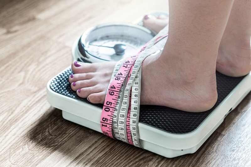 Feet tied up with measuring tape to a weight scale