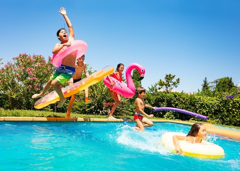 Group of Kids jumping into the pool with Inflatables