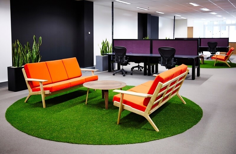 Interior area in a office with colourful orange sofas, with Herman Miller Aeron chairs