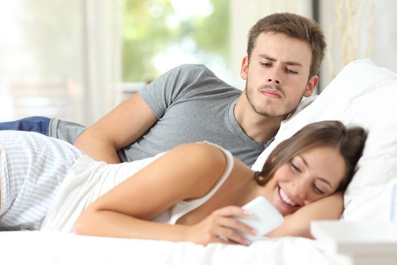 Jealous husband watching his wife mobile phone on the bed