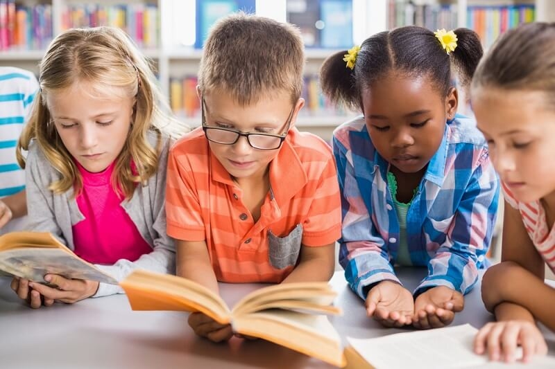 Kids reading a book in library at school