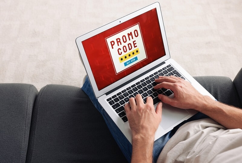 Man holding laptop using promo code for online shopping