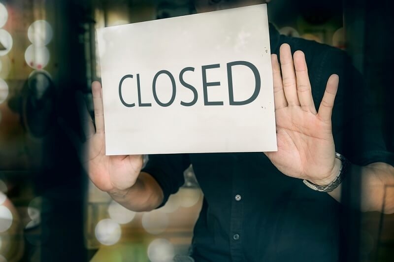 Man putting closed sign in window in shop