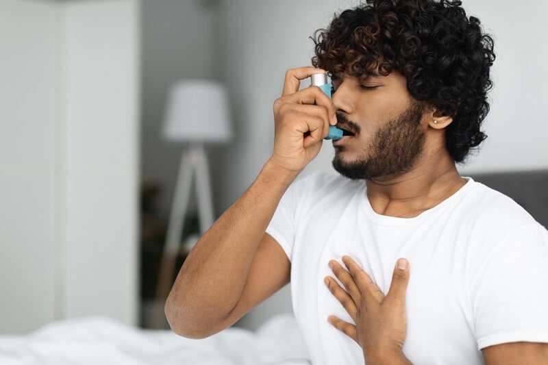 Man suffering from asthma, using inhaler