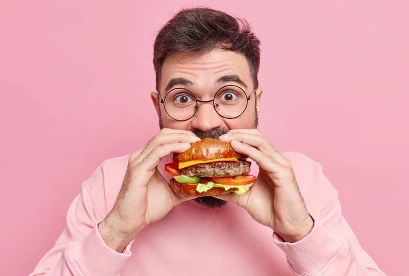 Man with glasses eating delicious hamburger