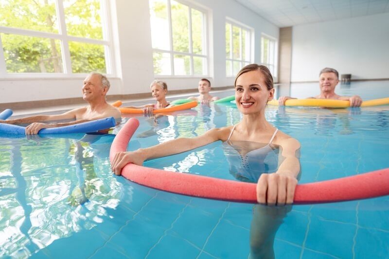 Patients during remobilization in a health center doing aquarobics in the water of a pool