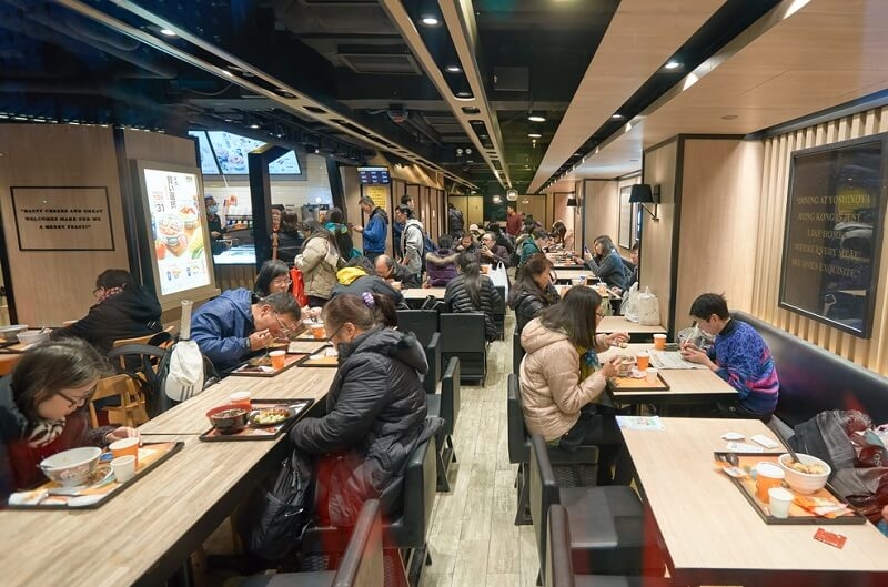 People eating inside Yoshinoya restaurant.