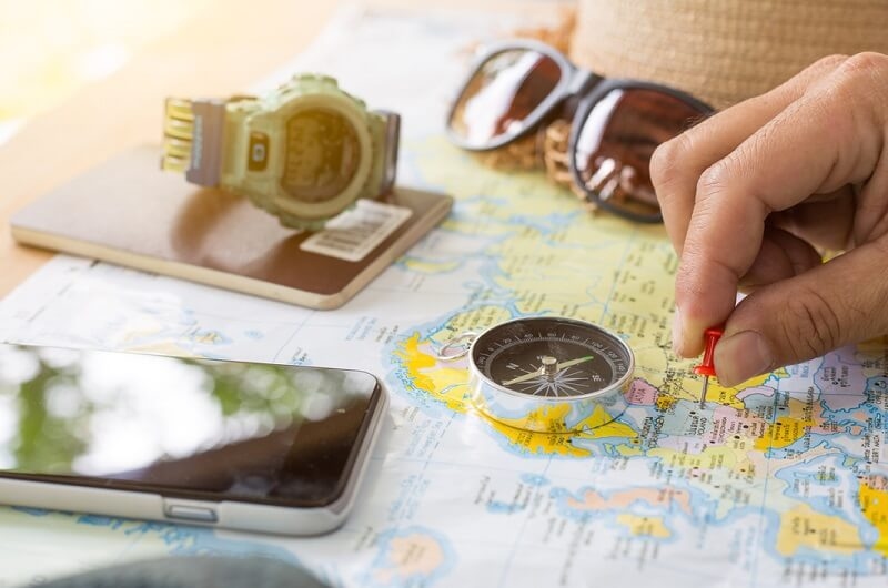 Person hand pinning travel destination on map