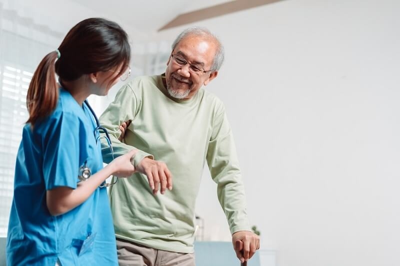 Physiotherapist helping patient get up from wheelchair for practice walking