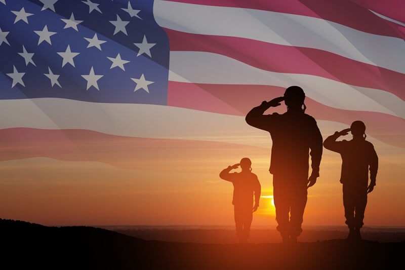 Silhouettes of soldiers saluting on background sunrise and USA flag