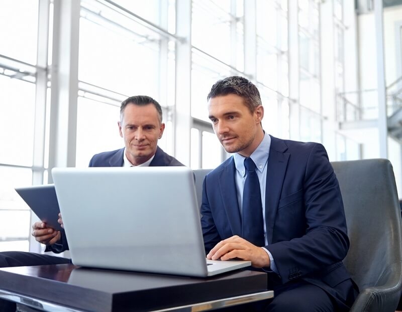 Two man in suit using laptop