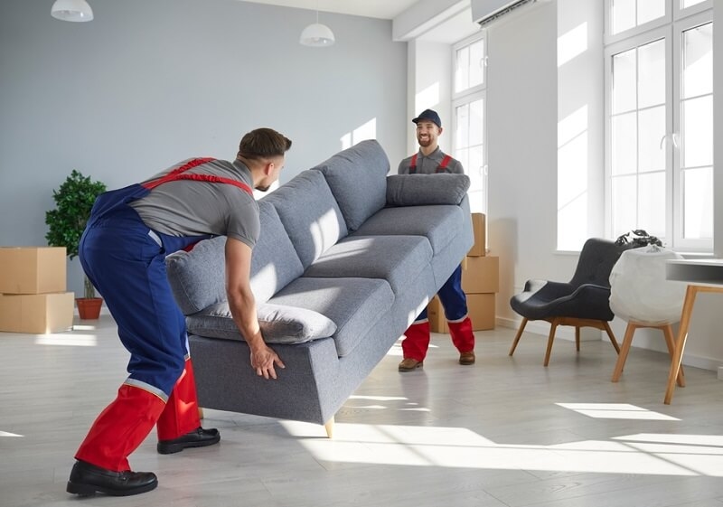 Two workers lifting up sofa, return shipping or drop-off concept