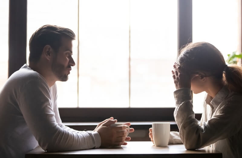 Upset woman and man talking in cafe about problem in relationships