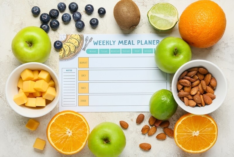 Weekly meal planner and different healthy foods on background