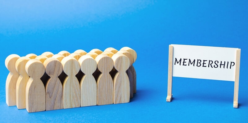 Wooden human figure and a poster with the word membership