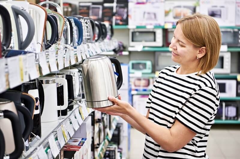 Woman customer choosing electric kettle from store