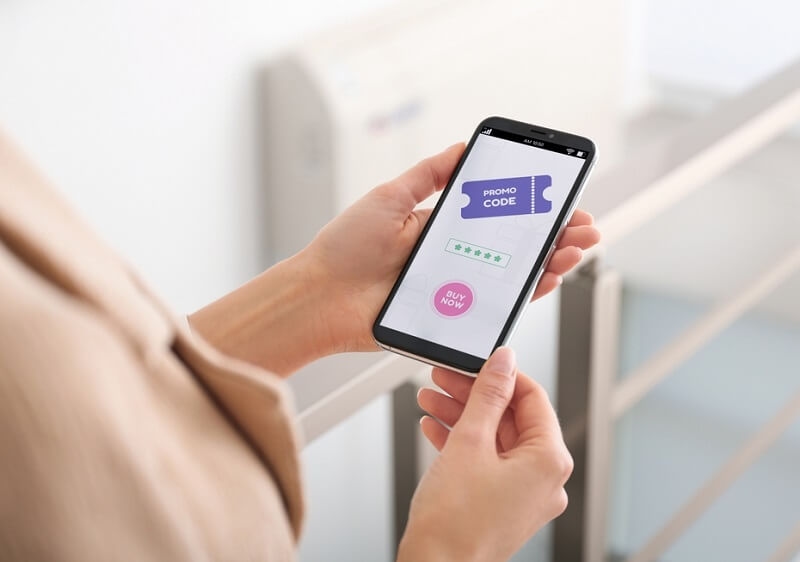 Woman holding smartphone with activated promo code in online shopping