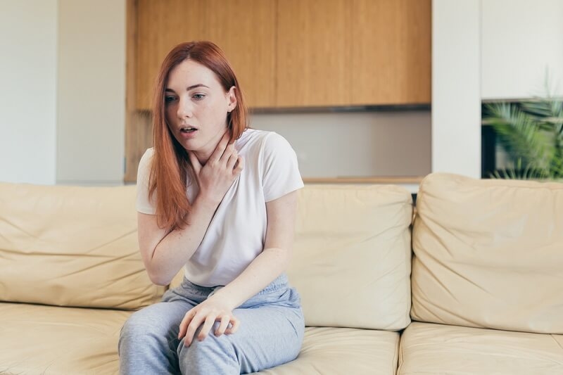 Woman sitting on couch having problem breathing