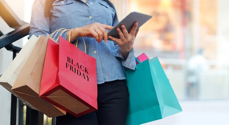 Woman using tablet and holding Black Friday shopping bag