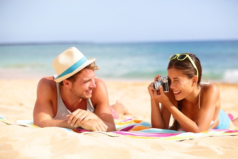 Woman taking photo of man on beach