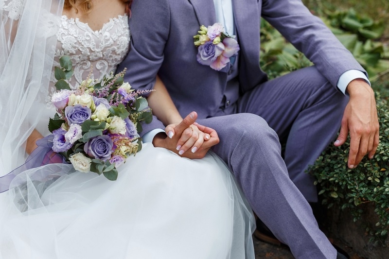  Bride holding bouquet and embracing groom in Very Peri suit