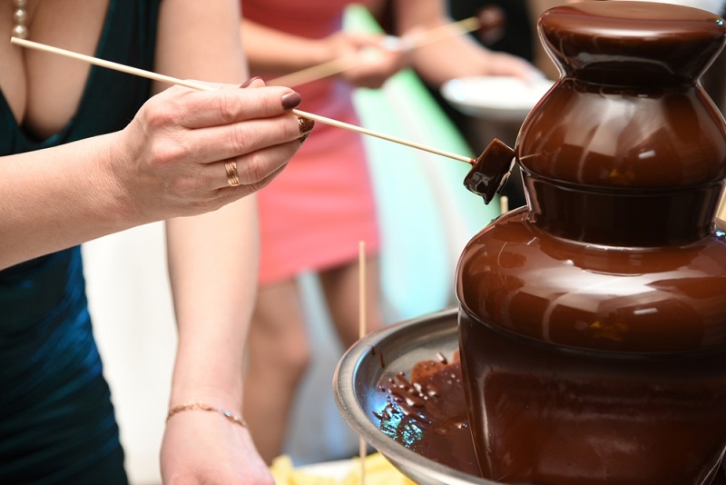 Woman takes some chocolate from Decadent chocolate fountain