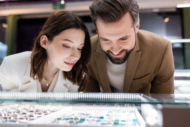 couple choosing wedding rings near showcase in jewelry shop