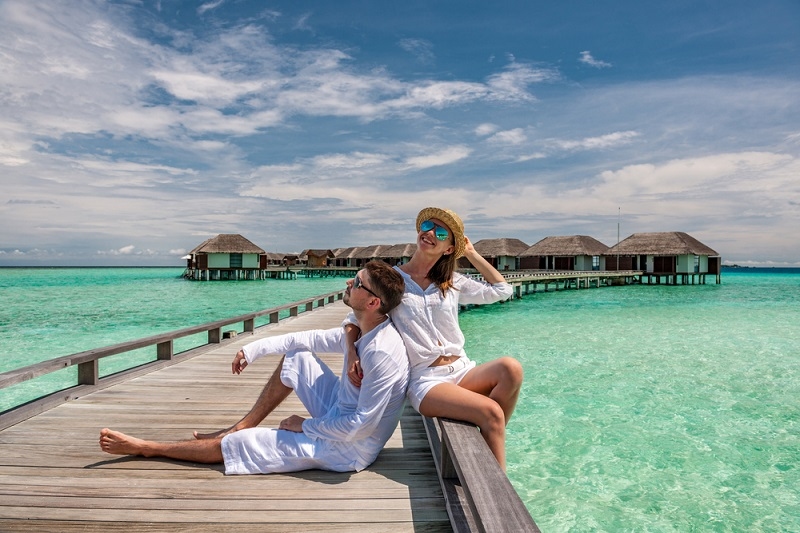 Couple in white on a tropical beach jetty at Maldives