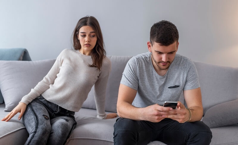 distrustful girlfriend annoyed with boyfriend holding phone texting