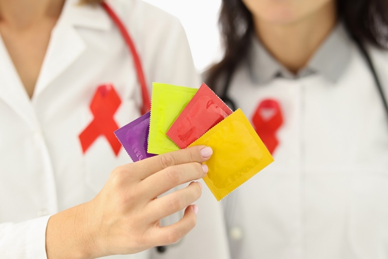 Doctors in white coats hold package of condoms