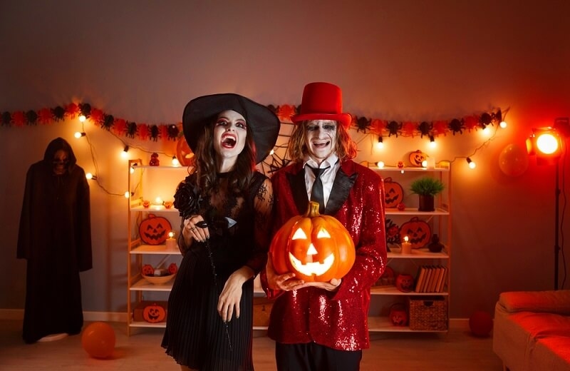 happy couple in spooky costumes with Jack-o-lantern