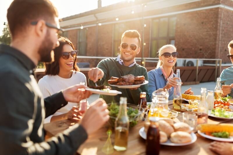 happy friends eating and drinking at barbecue party