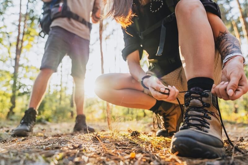 hiker tying shoelaces and getting ready for trekking in forest