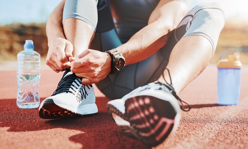 man Tying sports shoe getting ready for fitness training outdoors