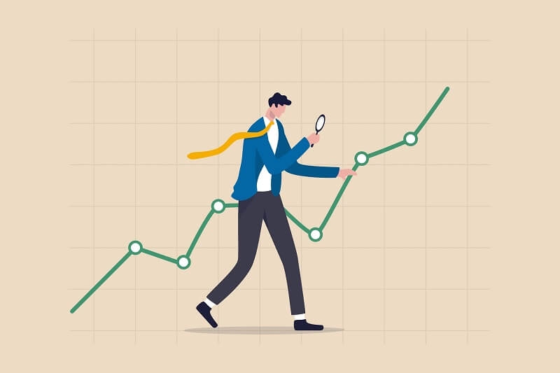 man using magnifying glass looking on market data rising graph