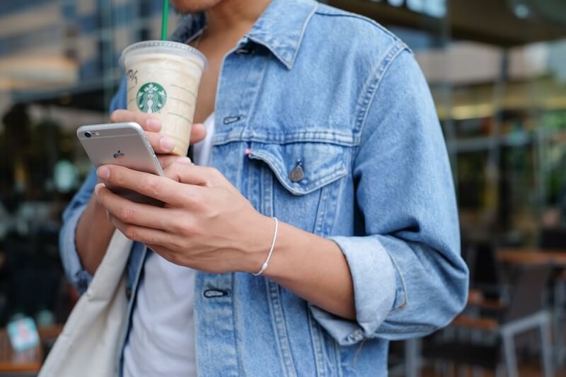 man hand holding iphone and drinking starbuck coffee