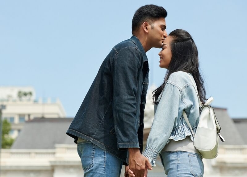  man kissing his smiling girlfriend on forehead