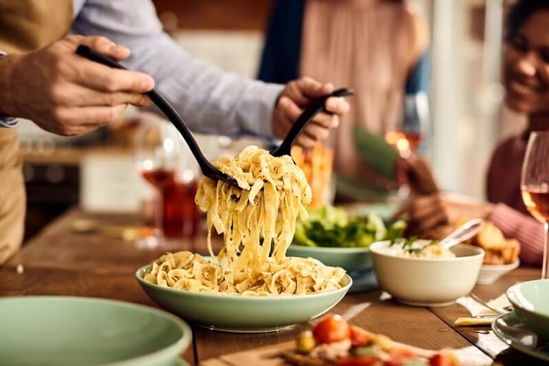 man serving pasta in dining table