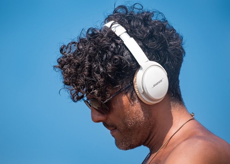 man wearing white Bose quiet comfort wireless headphones