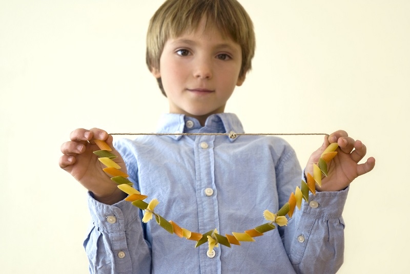 Child showing a selfmade pasta necklace