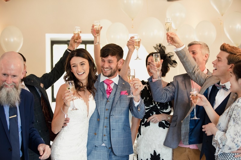 Bride and groom are dancing and raising their glasses with the guests